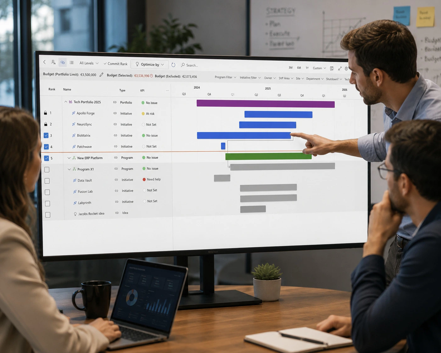 A team is assembled in a conference room discussing their various portfolio projects on a large monitor.